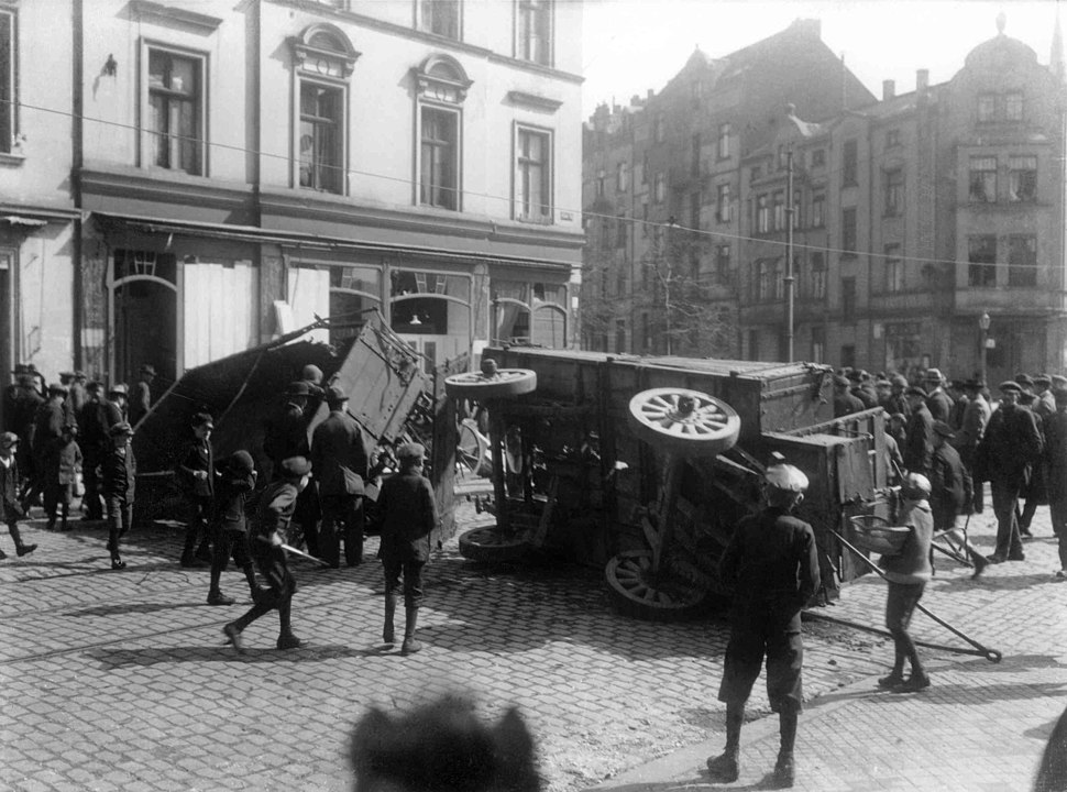 Group of men and boys surround overturned wagons in the middle of a street in Berlin