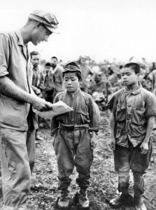 Two small Japanese boys in military fatigues speaking with American soldier in Okinawa