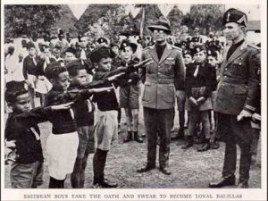 Eritrean children raise their right hand in a salute as they vow allegiance to the National Fascist Party while other children and men look on
