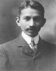 Photographic portrait of a young Mahatma Gandhi in a suit, looking into camera, as a young lawyer