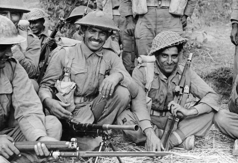 Indian Infantrymen in military dress with helmets kneeling and resting before going on patrol with some holding rifles