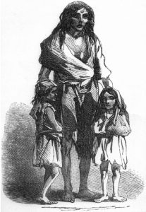 Woman standing with children on either side of her, all dressed in ragged clothes and appear malnourished