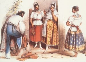 Three women in brightly patterned skirts and white tops and a man bending over wearing blue pants, white shirt and hat