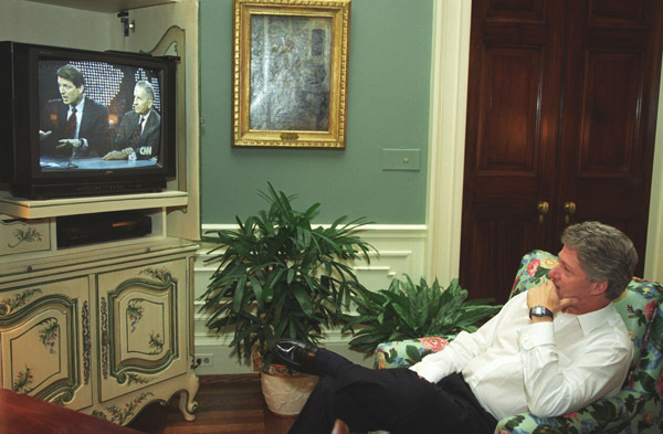President Clinton reclining in chair watching Vice President Gore debate Ross Perot on television