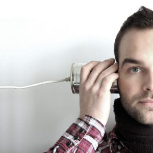 person with tin can telephone to ear