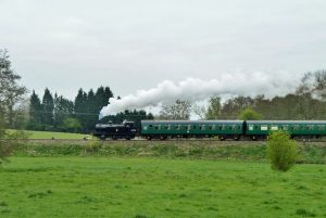 A steam powered train passes by on a flat landscape