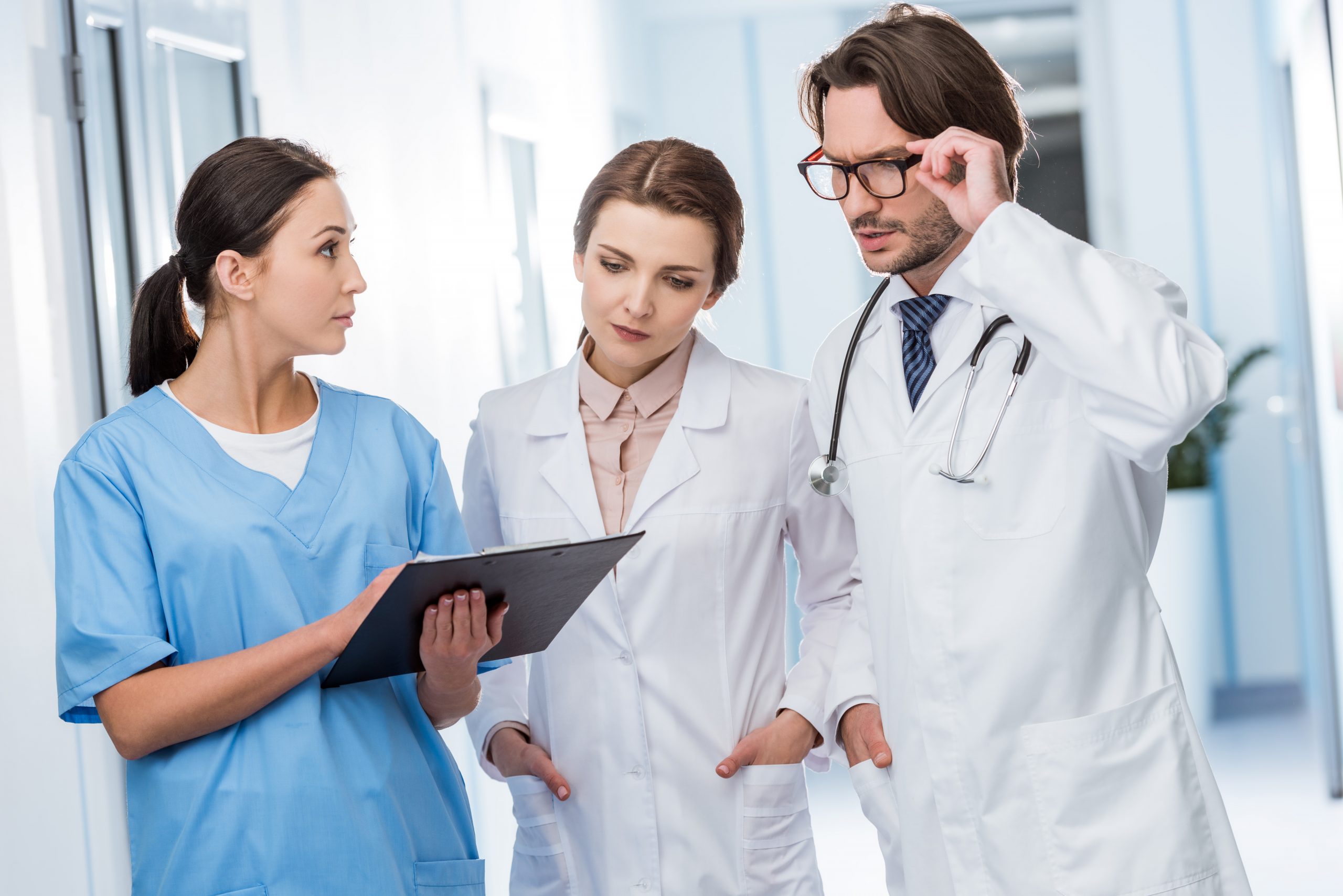 Image showing three medical staff standing together looking at a chart