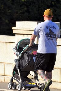 Photo of a man pushing a baby stroller.