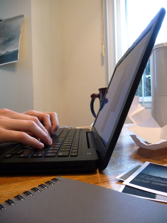 Side view of laptop with someone typing.
