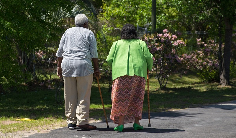 Two older individuals taking a walk while using walking canes for support.