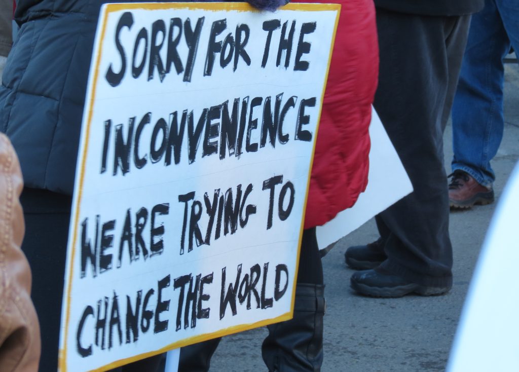Protest sign that reads "Sorry for the inconvenience we are trying to change the world."
