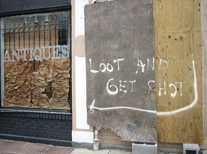 Photo of damaged antique store that reads "Loot and Get Shot."