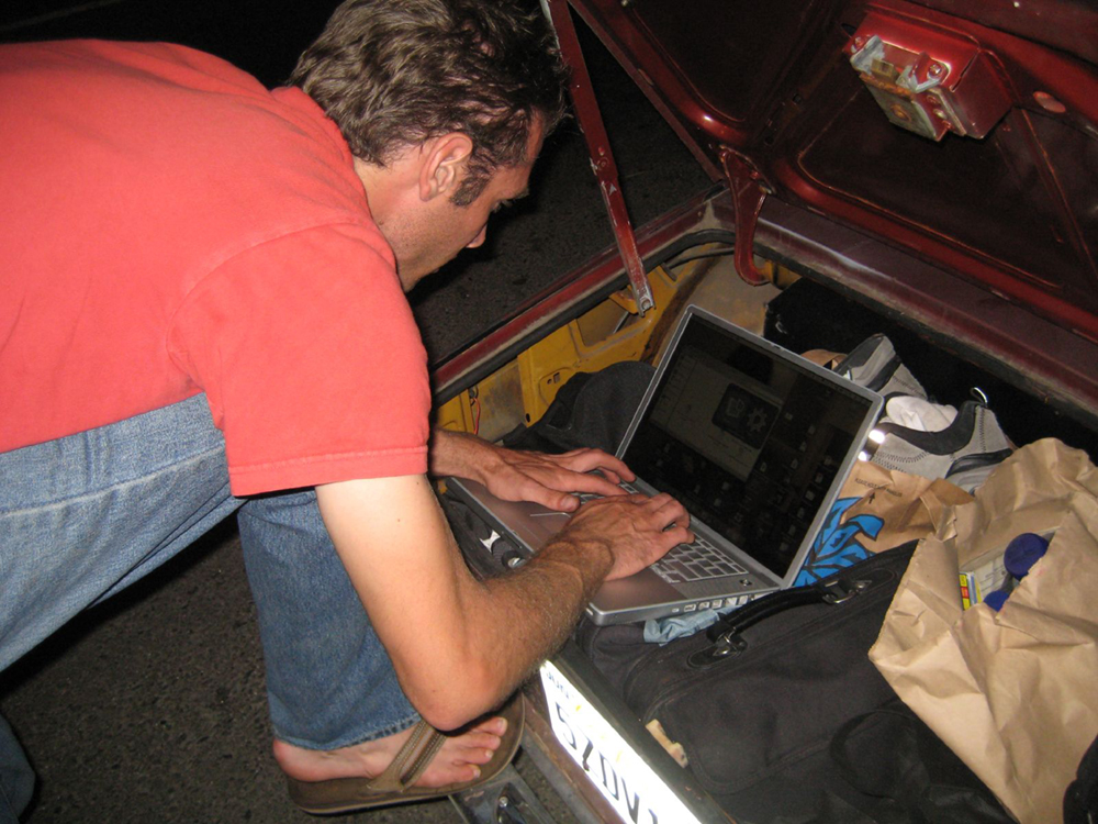 A man leaning over a laptop, typing