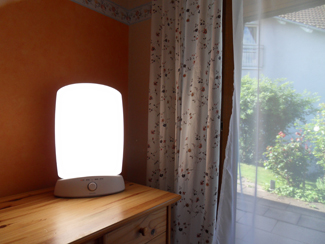 A photograph shows a bright lamp on a table next to a window.