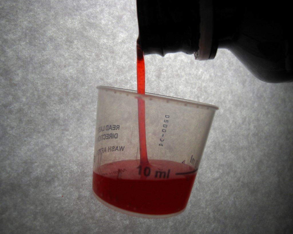 Cough Syrup being poured into a medicine cup