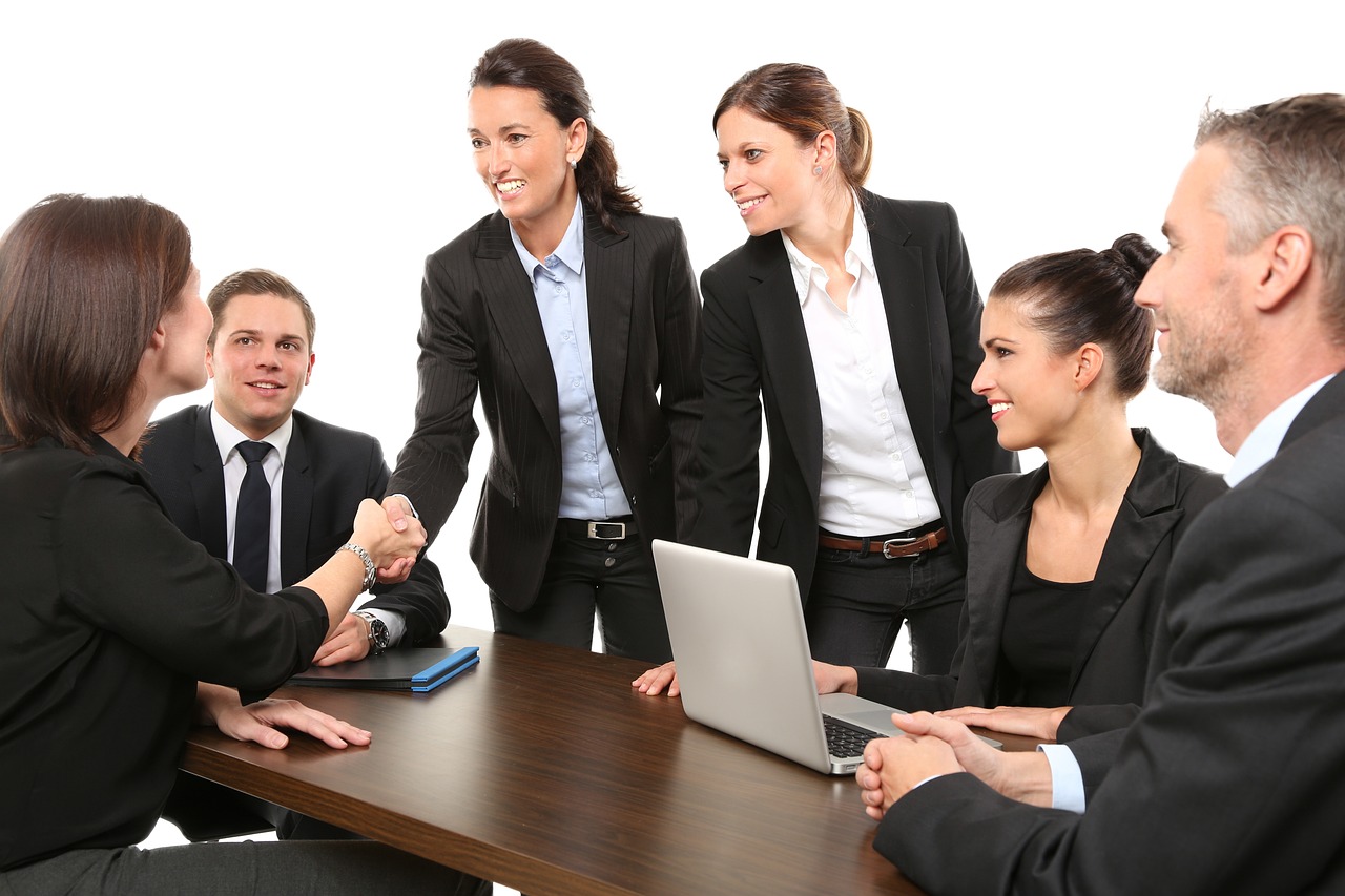 A group of people around a table greeting someone