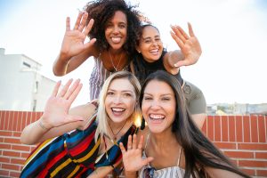 Four ladies smiling while holding one of their hands up