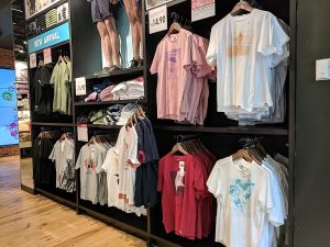 Inside of a clothing store with shirts on display for sale