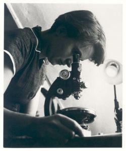 photo of Rosalind Franklin looking into a microscope.