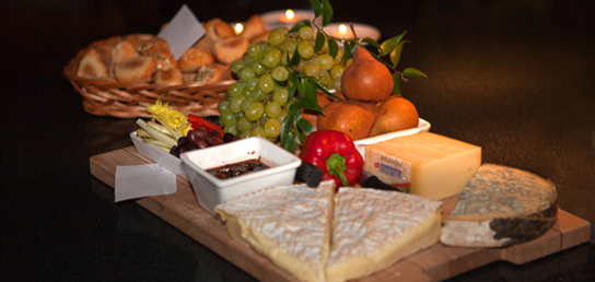 Photo shows a variety of cheeses, fruits, and breads served on a tray.