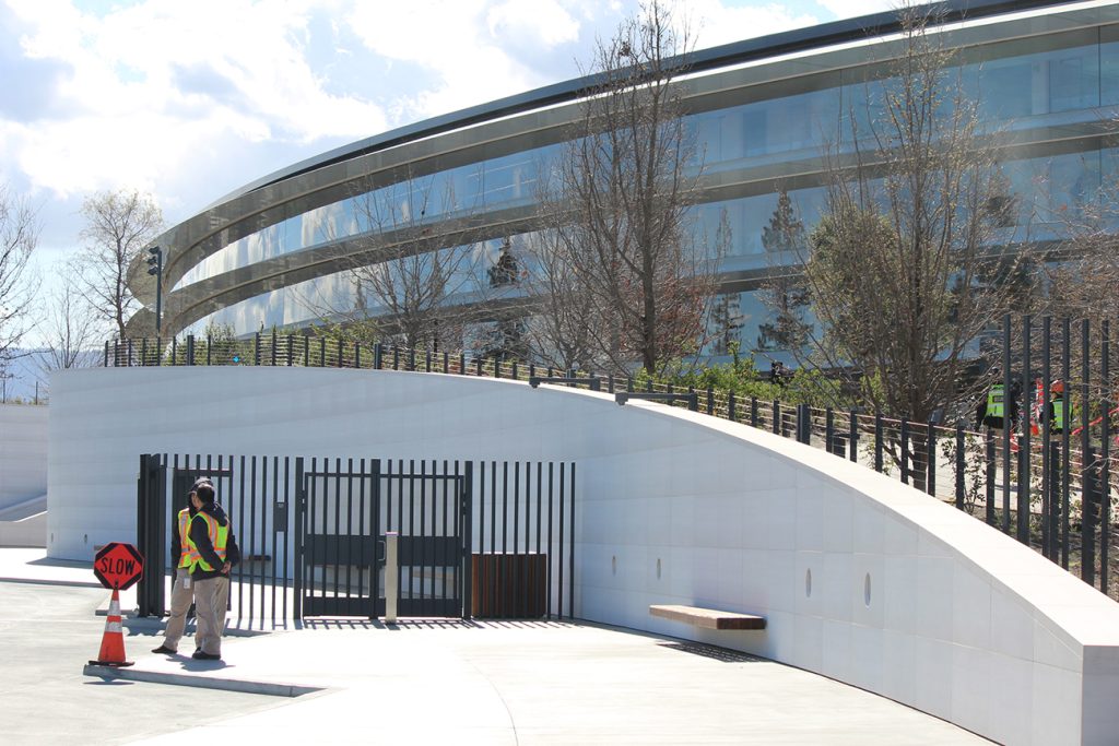 A photograph shows a large building made up of mostly windows, with a security gate out front.