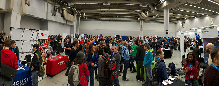 Photo of a group of people in an open rm with tables set up.