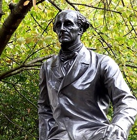 A photograph of a statue with the likeness of John Stuart Mill.