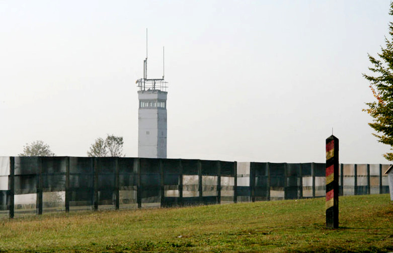 A fence along the former border between East and West Germany with a tower on one side