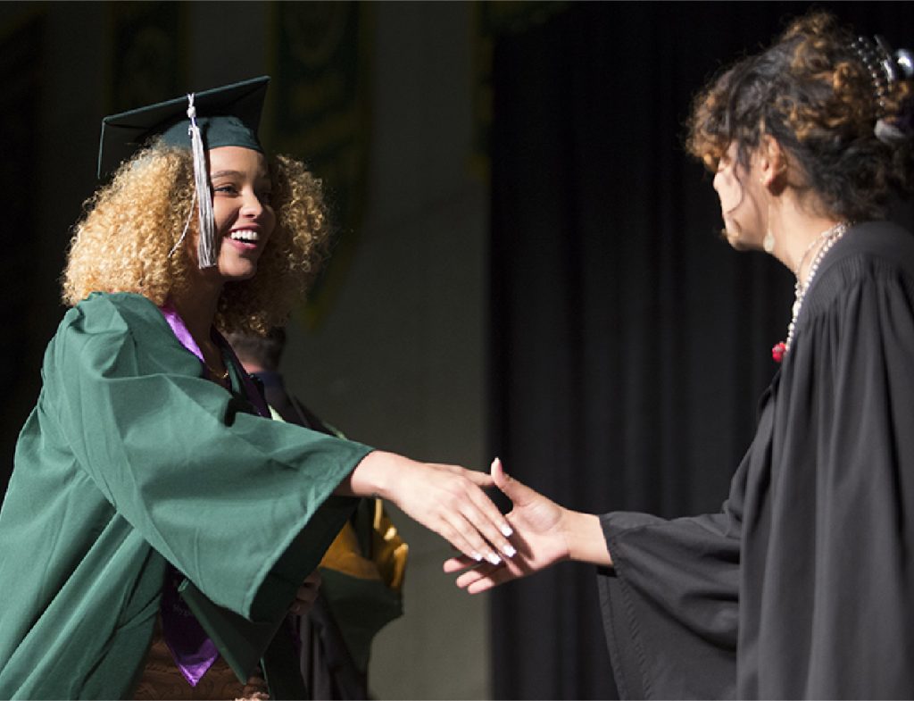 A college student walking across the stage at a graduation ceremony.