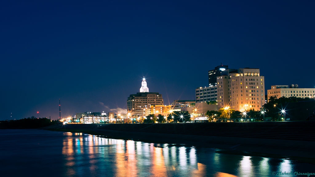 Night view of Downtown Baton Rouge, Louisiana with the river in the foreground reflecting the lights of the city.