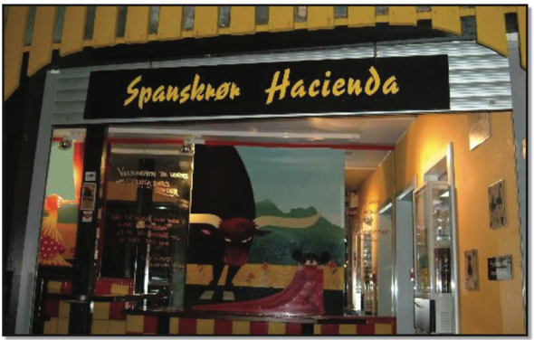 Restaurant with red and yellow coloration with a poster of a bull fighter and bull dead center in the front window.