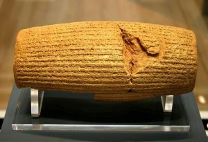 Picture of the cyrus scroll, a clay cylinder with cuneiform writing.