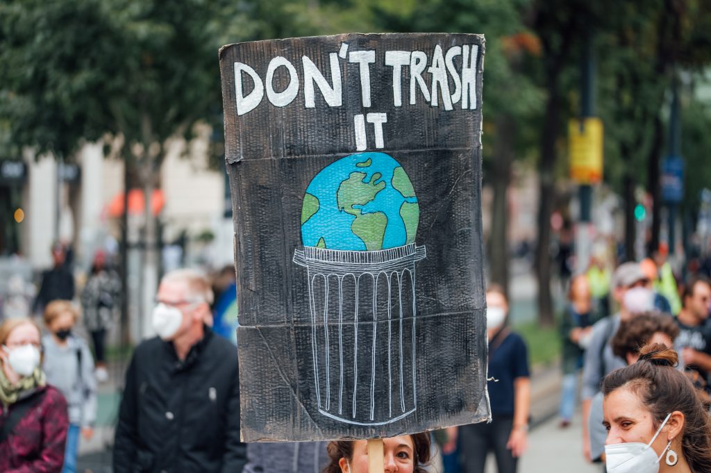 Protest sign at a climate protest saying "Don't Trash It" with a drawing of the Earth in a garbage can