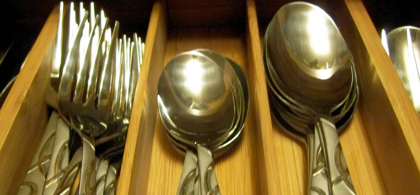 A drawer with three types of silverware in a wooden case.
