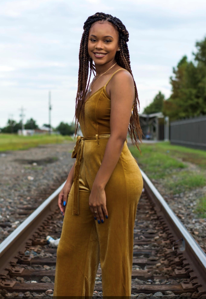 Photo of a teen girl standing on railroad tracks.