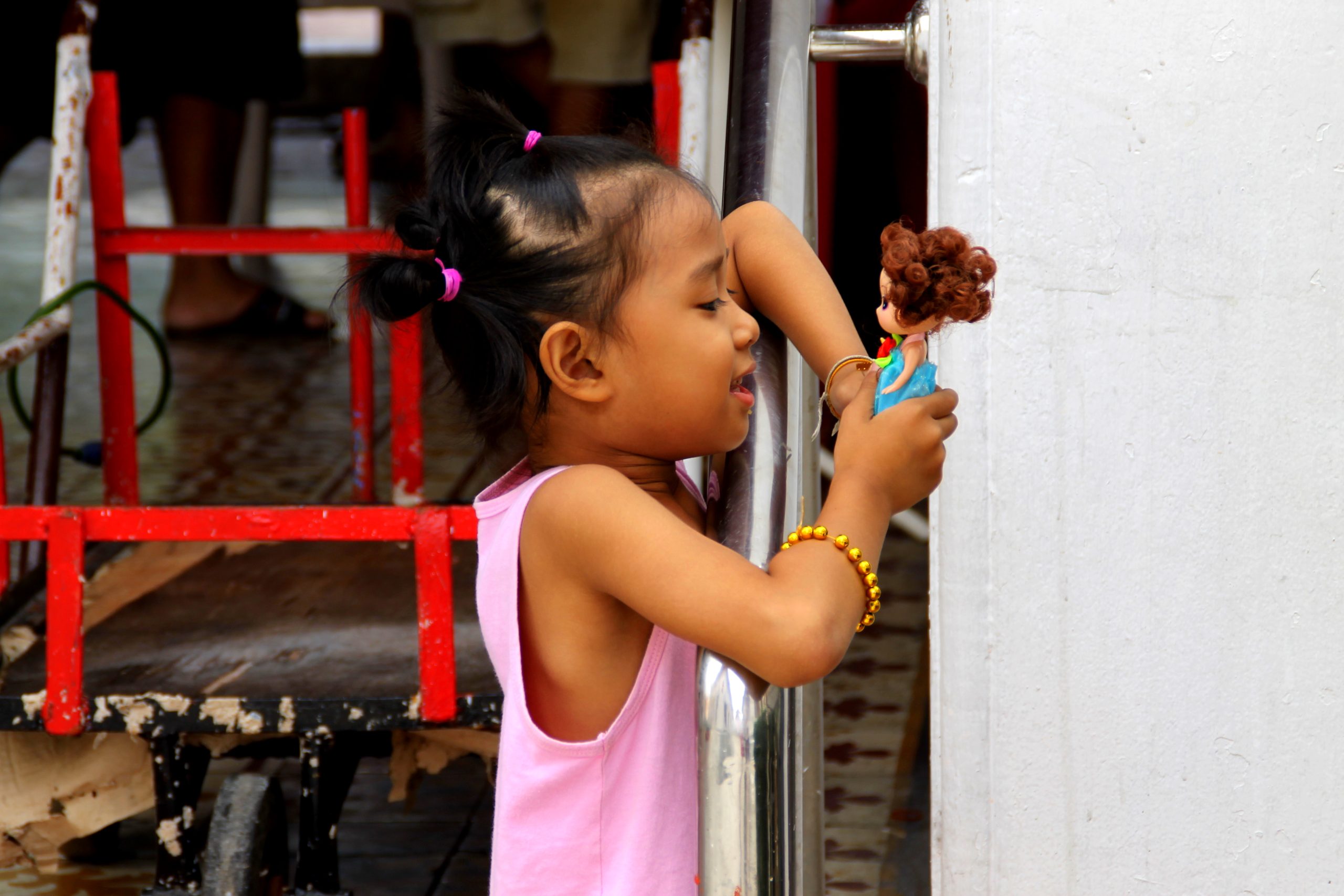 Small girl from Bangkok playing with a tiny play doll.