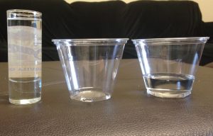 Photo of three clear containers. Two are partially filled with water. The other is empty.