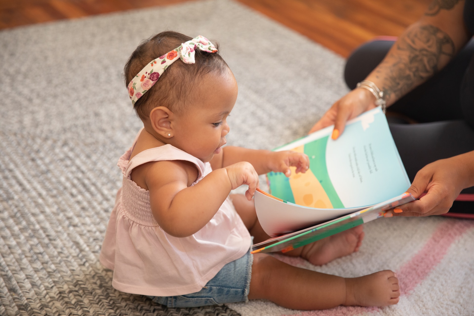 The photo shows a toddler looking at a picture book.