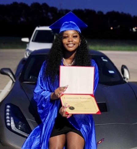 The photo shows a girl posing with her diploma on high school graduation day.
