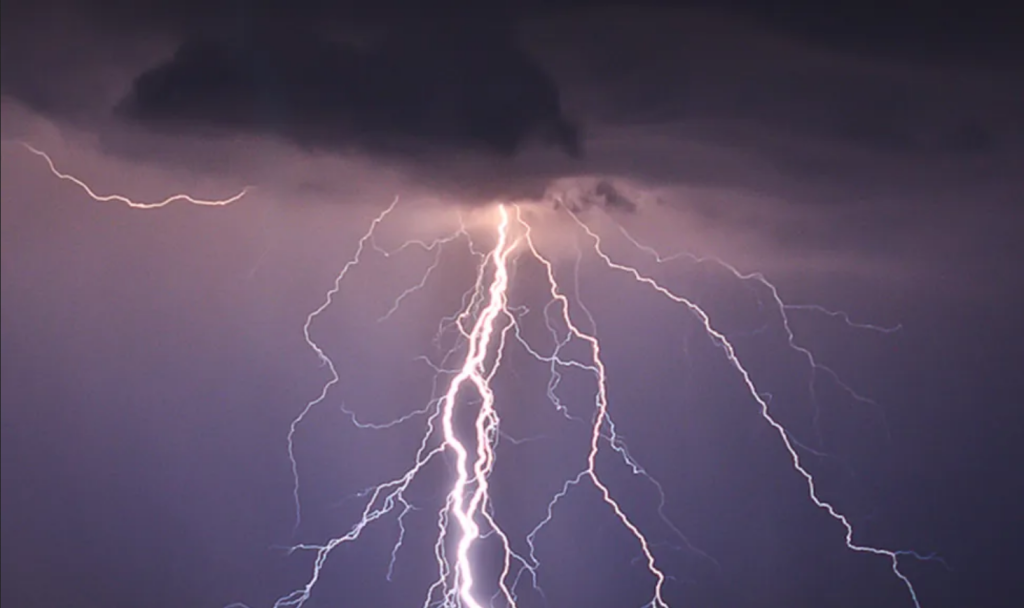 This photo shows branch lightning coming from a dark cloud and hitting the ground.