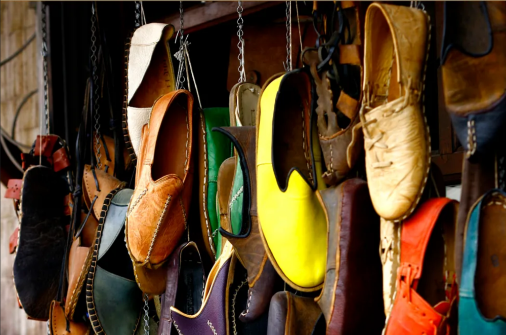 This photo shows many different pairs of shoes in various colors. The shoes appear to be hanging from a wall by cords.