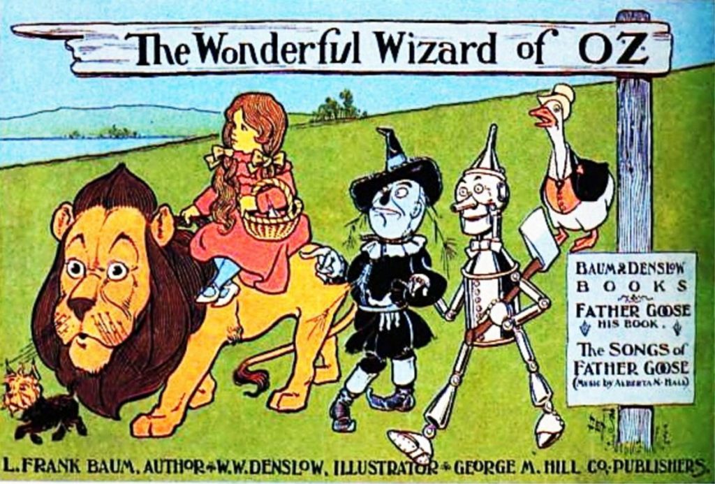 A book cover entitled The Wonderful Wizard of OZ shows the Cowardly Lion, the Scarecrow, the Tin Woodsman, Dorothy (who rides atop the Lion), and Toto on their journey. Father Goose, whose stories and songs are also present in the book, follows behind.