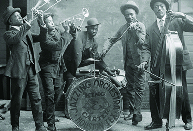 A photograph shows a group of Black jazz musicians playing their instruments. A drum reads “Jazzing Orchestra / King and Carter / Houston Tex.”