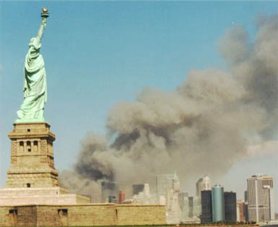 A photograph shows the New York skyline with the Statue of Liberty in the foreground. In the background, massive plumes of smoke rise from the twin towers.